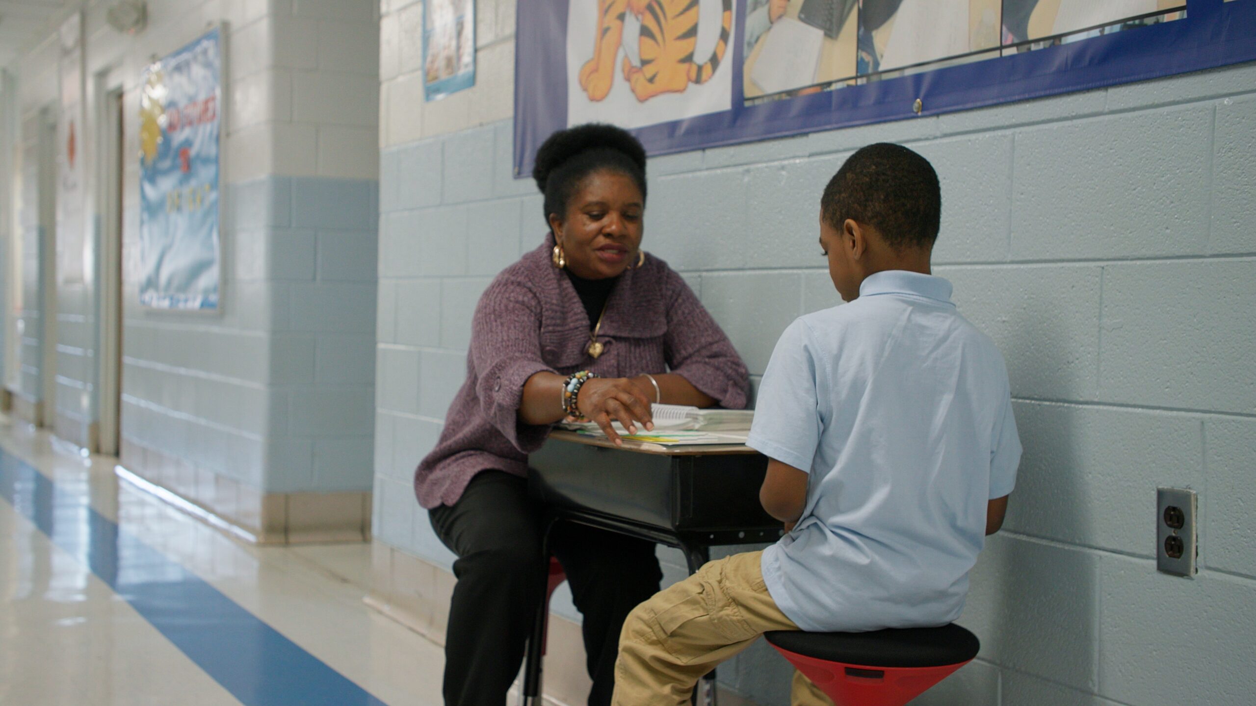 Tutor sitting with student in school hall